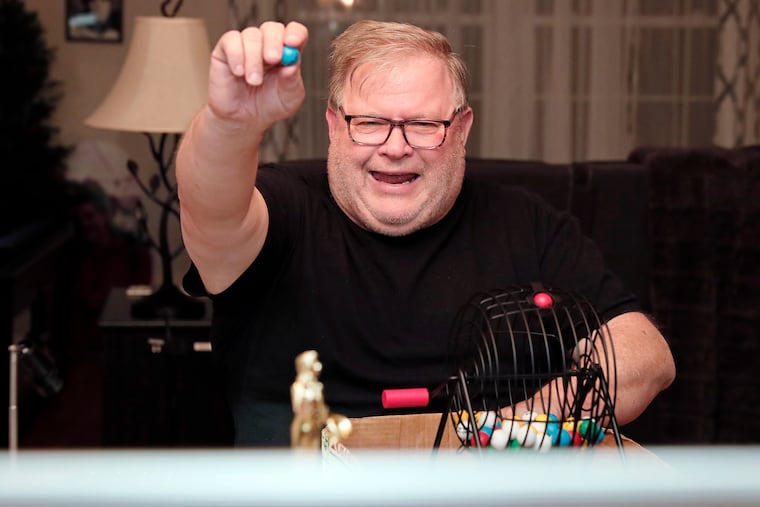 John Langenstein holds up a ball and calls the number during ”Pandemic Bingo" Week 47 from the dining room table of the Langenstein family's Willow Grove, Pa. home on March 5.