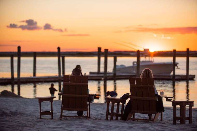 Two people watching the sunset on the bay with a drink at the Deauville Inn in Strathmere, NJ.