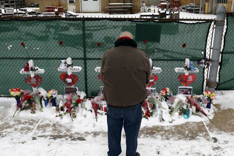 A man prays at a makeshift memorial Sunday, Feb. 17, 2019, in Aurora, Ill., near Henry Pratt Co. manufacturing company where several were killed on Friday. Authorities say an initial background check five years ago failed to flag an out-of-state felony conviction that would have prevented a man from buying the gun he used in the mass shooting in Aurora. (AP Photo/Nam Y. Huh)