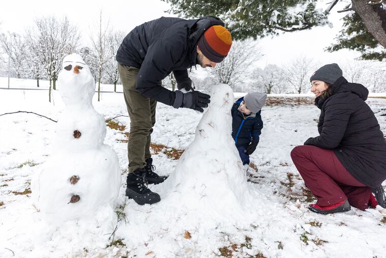 (From left to right) Edmundo Ruiz, father, Alexander Ruiz Rapier, 2, son, and Renee Rapier, mother, who live in Fairmount build Olaf the snowman and Elsa from the Disney movie Frozen at a Philly park on Saturday.