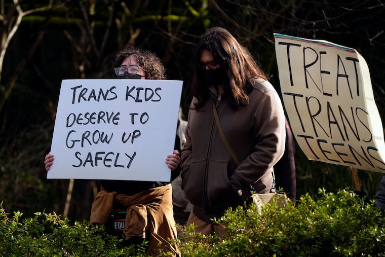 FILE - People wave signs to passing cars during a pro-transgender rights protest outside of Seattle Children's Hospital after the institution postponed some gender-affirming surgeries for minors following an executive order by President Donald Trump, Sunday, Feb. 9, 2025, in Seattle. (AP Photo/Lindsey Wasson, File)