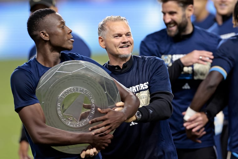 Union head coach Bradley Carnell (right) and midfielder Danley Jean Jacques (left) celebrate after the team won the Supporters' Shield trophy on Saturday by clinching MLS's best regulr-season record.