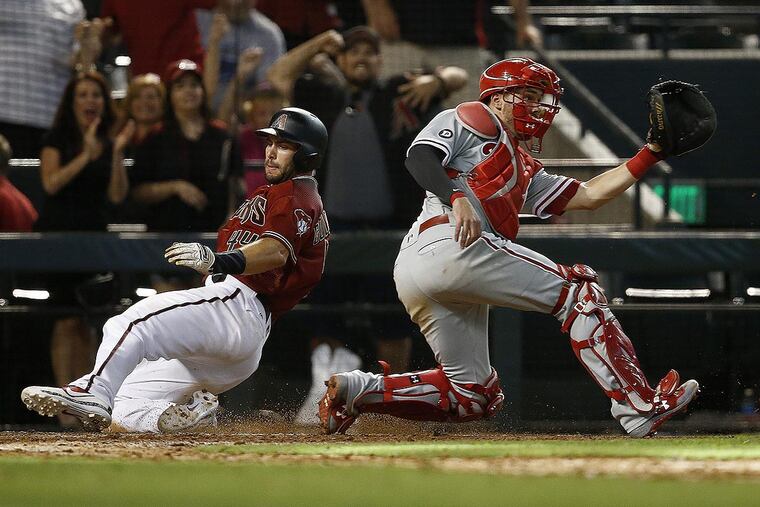 Arizona Diamondbacks' Paul Goldschmidt, left, scores the winning run as Philadelphia Phillies' Andrew Knapp, right, waits for a late throw during the 11th inning of a baseball game Sunday, June 25, 2017, in Phoenix.
