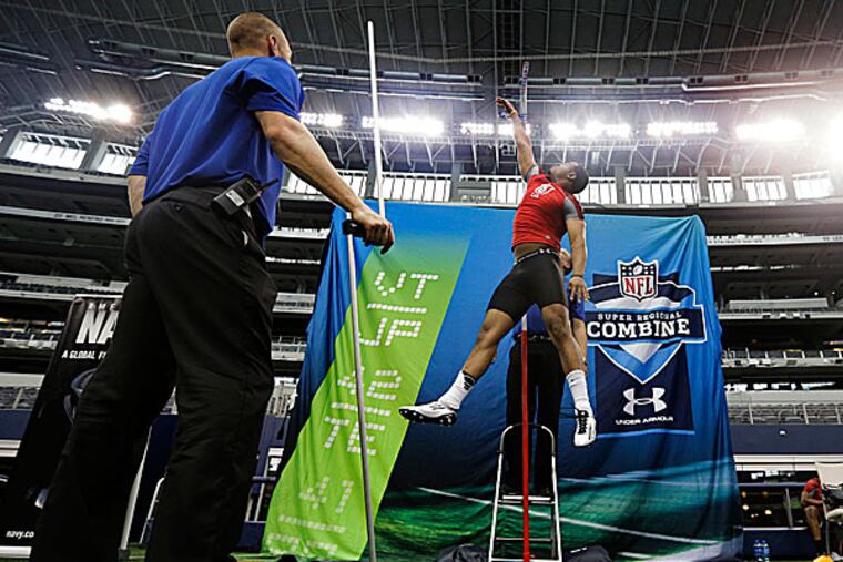 Combine staff member Mike Kozak watches as tight end John Reese tests in the vertical leap. (Tony Gutierrez/AP)