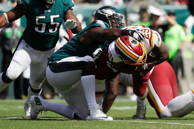 Fletcher Cox wrangles Washington running back Derrius Guice to the ground Sunday as Brandon Graham looks on. Cox, linebacker Nigel Bradham and guard Brandon Brooks did extra work in the preseason as they recovered from injuries and played well in the season-opening win.