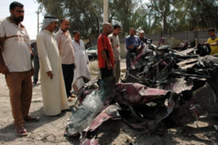Residents gather around the wreckage of a minibus about 20 miles south of Baghdad. A roadside bomb struck the vehicle yesterday, killing eight people, police said.