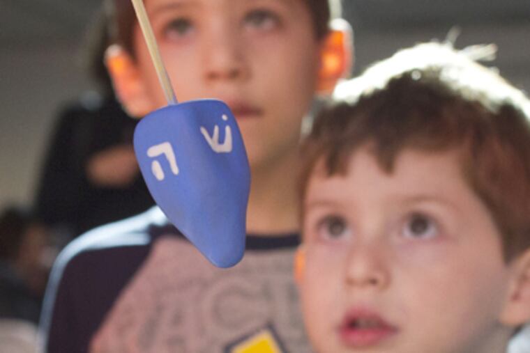 Brothers Bennett, 6, and Jonah Kutikov, 4, watch the dreidel-making demonstration put on by the Clay Studio at the National Museum of American Jewish History. (David M Warren / Staff Photographer)