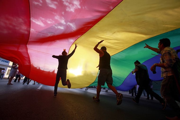 Attendees of Philadelphia's Pride celebrations run under a large Pride flag outside of the William Way LGBT Community Center in Philadelphia in 2025.