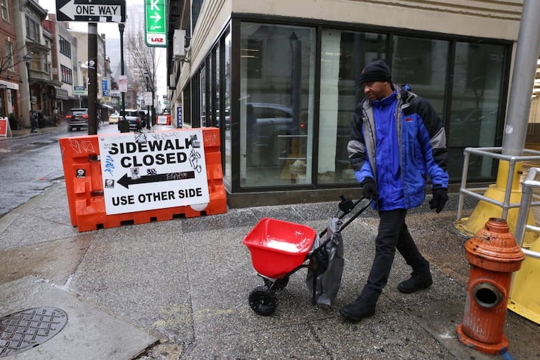 Alpha Souare salts the sidewalk on 15th Street ahead of the pending snow storm in Philadelphia on Wednesday, March 7, 2018.