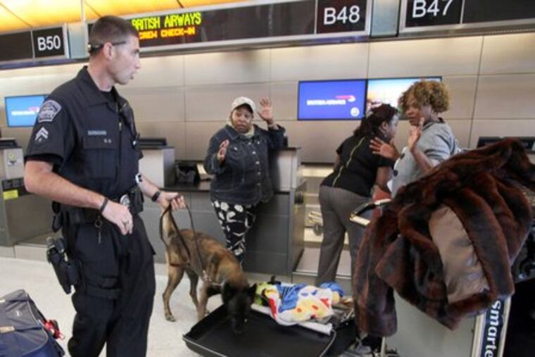 Officer Mike Manahan, with search dog Baxo, checks passenger's bag at Tom Bradley International Airport in Los Angeles.
