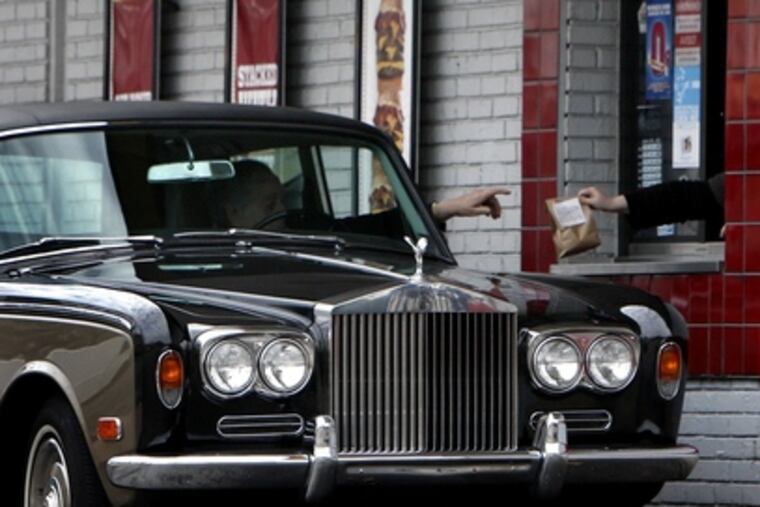 YA GOTTA SAVE those pennies somewhere. An unidentified motorist driving a Rolls Royce stops at the takeout window of a Burger King in Northeast Philadelphia yesterday.