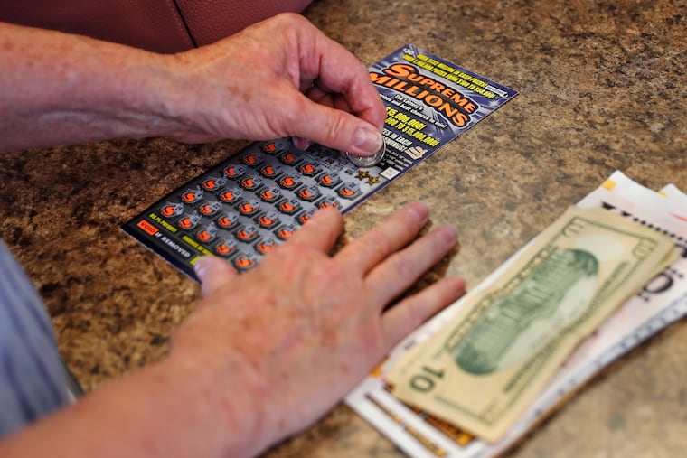 A woman scratches a $30 instant ticket while playing the lottery in Methuen, Mass. The coronavirus pandemic has been a rollercoaster for state lotteries across the country.