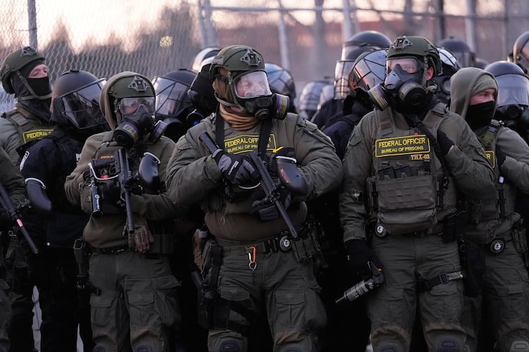 Federal officers stand outside the Bishop Henry Whipple Federal Building during a protest on Saturday in Minneapolis.