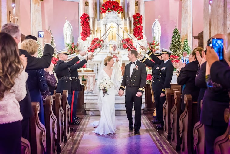 Chip O'Connell and Elizabeth Convery walk beneath an arch of swords.