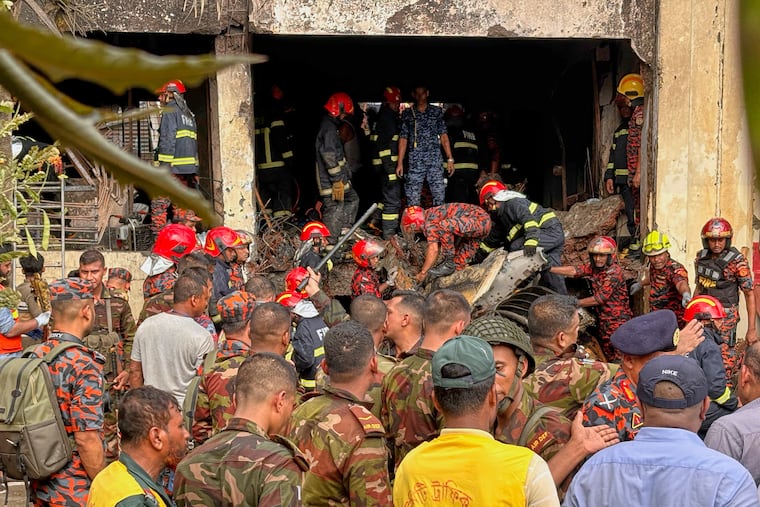 Firemen check the wreckage of a Bangladesh Air Force training aircraft that crashed onto a school campus in Dhaka, Bangladesh, on Monday, July 21, 2025.