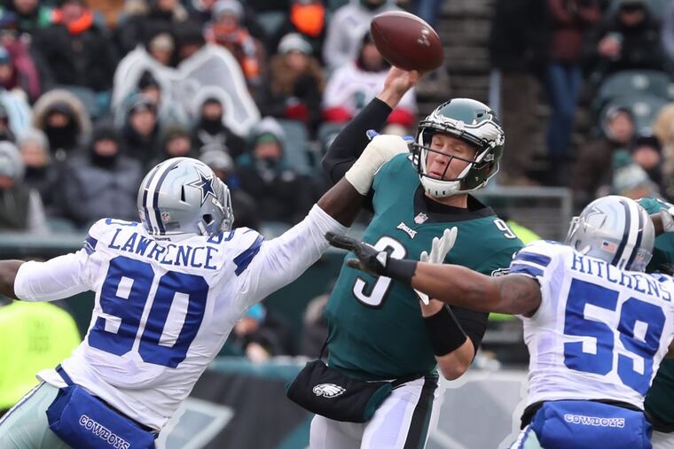 Eagles quarterback Nick Foles is hit while he is throwing the ball by Dallas’ Demarcus Lawrence (90) and pressured by Anthony Hitchens (59) in the first quarter of Sunday’s game.