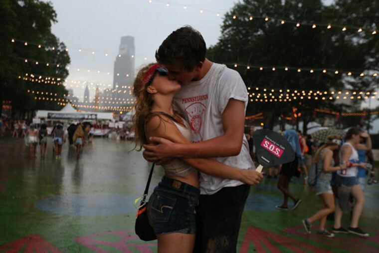 As storms forced concertgoers to temporarily vacate the Made in America concert, Scott Lambert and a young woman named Natalie shared a kiss on Aug. 31, 2014. ( DAVID MAIALETTI / Staff Photographer )