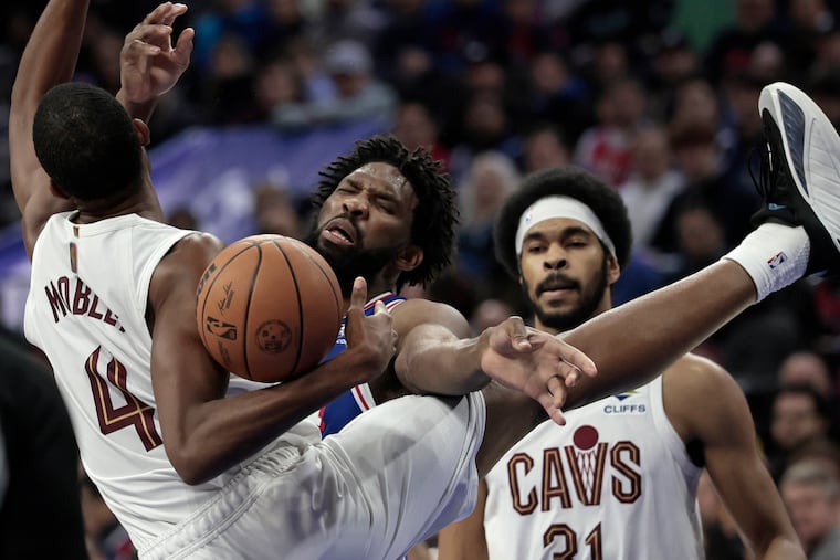 Sixers' Joel Embiid (center) is fouled by Cleveland's Evan Mobley during their matchup on Wednesday.