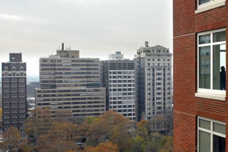 A guest (in window at far right) at yesterday's opening takes in the view at 10 Rittenhouse Square. (Tom Gralish / Staff)