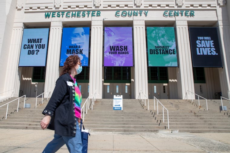A pedestrian wearing a face mask to protect for the coronavirus walks past a COVID-19 test site for first responders at the Westchester County Center.