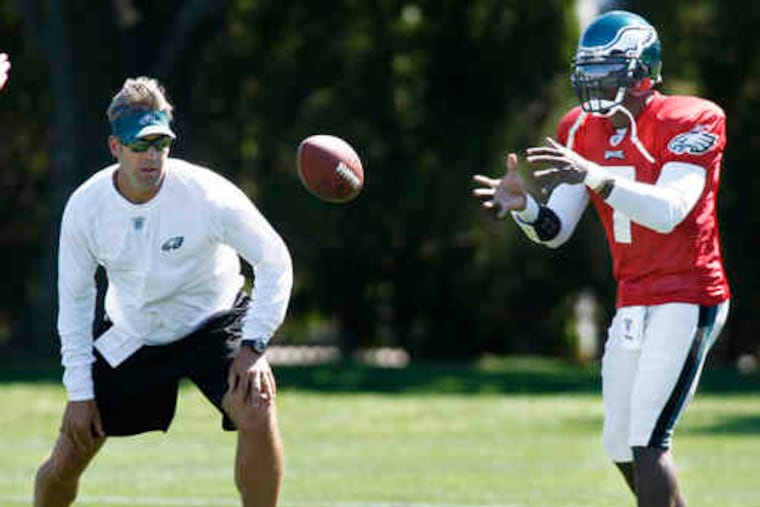 Michael Vick takes a practice snap as Eagles assistant coach Doug Pederson watches. Vick will start at Detroit on Sunday.