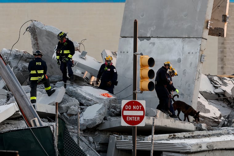 Firefighters and Pennsylvania Urban Search and Rescue look through the site of the partial parking garage collapse in Grays Ferry on Sunday, April 12, 2026 in Philadelphia.