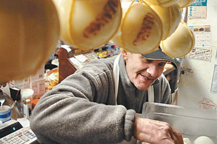 Philip Mancuso has a way with curds. Over the decades, he has seen the fortunes of the East Passyunk shopping district molder and ripen from his cheese shop. Nineteen businesses have opened there in the last year. The new mix “keeps the avenue authentic,” another store owner says. (TOM GRALISH / Staff Photographer)