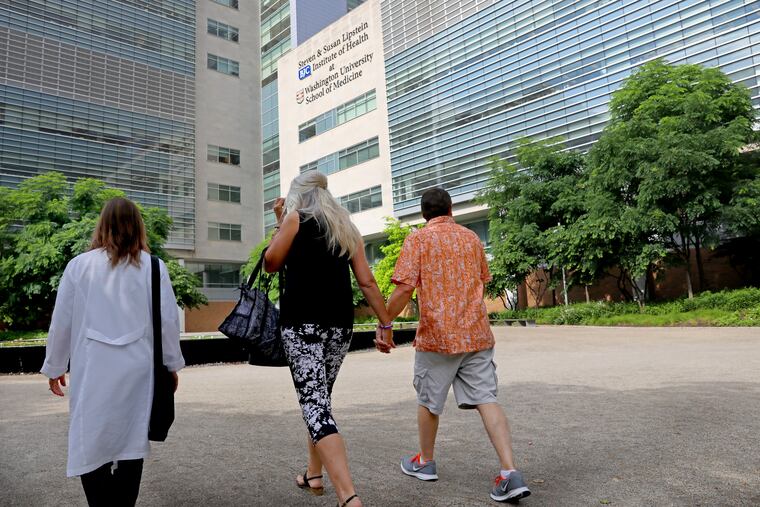 Dean DeMoe, right, and his wife, Deb DeMoe, center, of North Dakota, walk across the campus of Washington University School of Medicine on May 30, 2018, with Tamara Donahue, to begin examinations for a study of people living with dominantly inherited Alzheimer's disease. Dean DeMoe has testing at the medical school yearly as part of the study. Donahue is the study coordinator. (Christian Gooden/St. Louis Post-Dispatch/TNS)