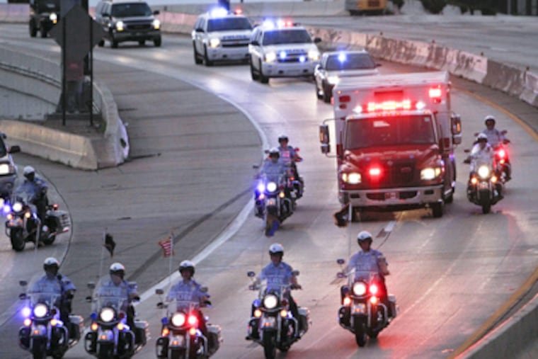 Police escort an ambulance carrying the body of veteran Philly Highway Patrol officer Brian Lorenzo to the medical examiners office, Sunday July 8, 2012. A Levittown man is charged with DUI in the crash. (Photo by Joseph Kaczmarek)