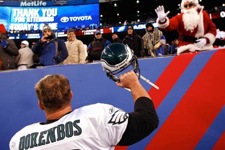 A fan dressed as Santa waves to Jon Dorenbos, left, as he celebrates the Eagles win over the New York Giants. (David Maialetti/Staff Photographer)