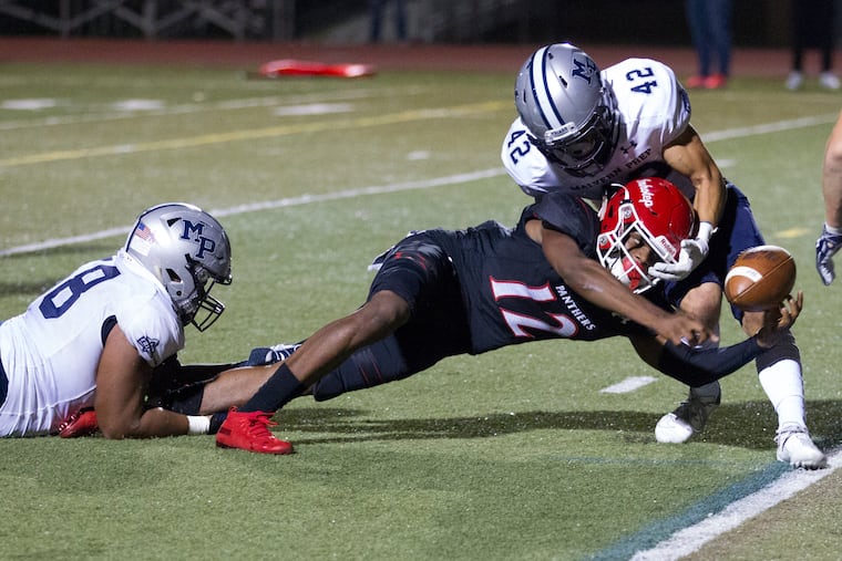 Jalen Sutton-Christian of Imhotep scores a touchdown against Cade Szostek (right) of Malvern Prep. Malvern's JT Roberts is grabbing Sutton-Christian's leg.