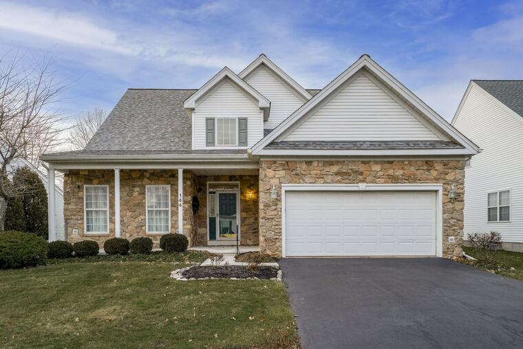 The stone-front house has a covered porch and features a two-story entry foyer with hardwood floors