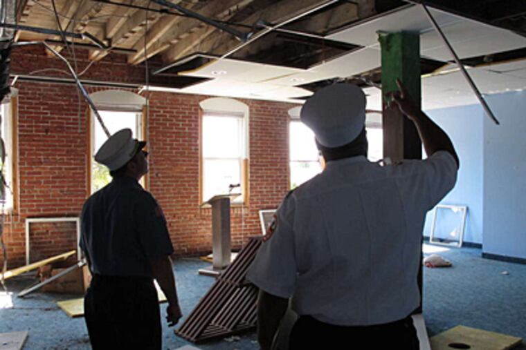 Camden fire officials check the damaged ceiling of an abandoned building. Findings are entered into a software program to aid emergency personnel. (Geoff Mulvihill/AP)