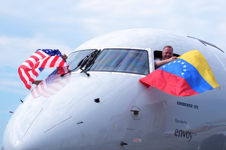 Capt. Ric Wilson waves a Venezuelan flag and the first officer waves a U.S. flag as they prepare to fly American Airlines Flight AA3599 from Miami on Thursday. It was the first direct commercial flight between the United States and Venezuela in seven years.