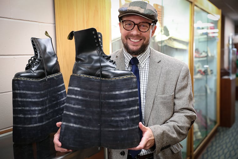 Curator Andrew Meyr holds an altered pair of Dr. Martens inside The Shoe Museum at Temple University's School of Podiatric Medicine in Center City.