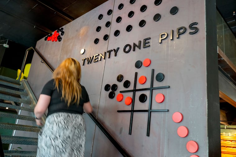 A magnetic tic-tac-toe game adheres to the steel wall leading up the stairs at Twenty One Pips in Ardmore, a new board game-themed restaurant.