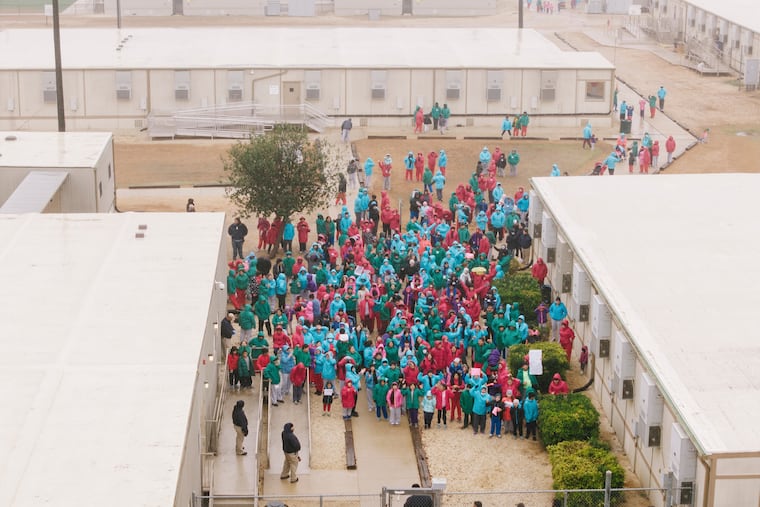 Detainees held at the South Texas Family Residential Center wave signs during a demonstration in Dilley, Texas, Saturday, Jan. 24, 2026. The Trump administration has awarded a $158 million contract to represent unaccompanied migrant children to the nonprofit Our Rescue.