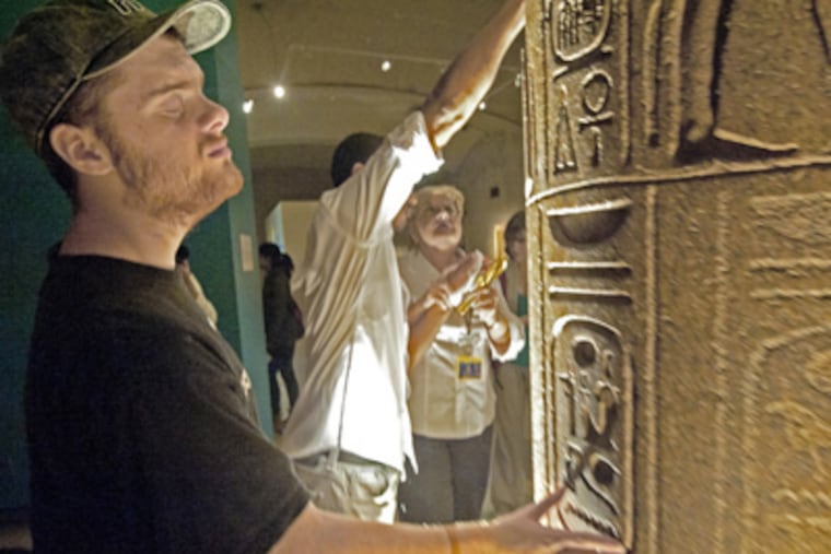 Anthony Coughlan, 19, touches hieroglyphs at the Penn Museum of Archaeology and Anthropology's Egyptian exhibits. (April Saul / Staff Photographer)
