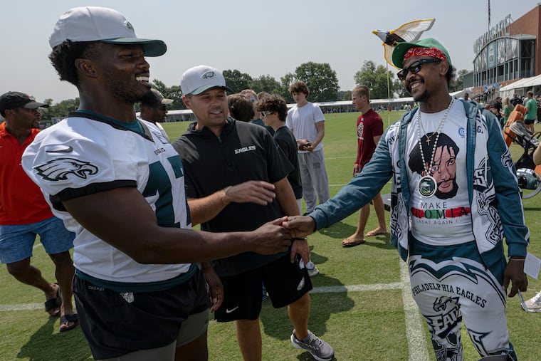 Eagles linebacker Nakobe Dean greets Mucha Nama, the rideshare driver famed for decorating his van in Eagles gear, after Monday's training camp practice.