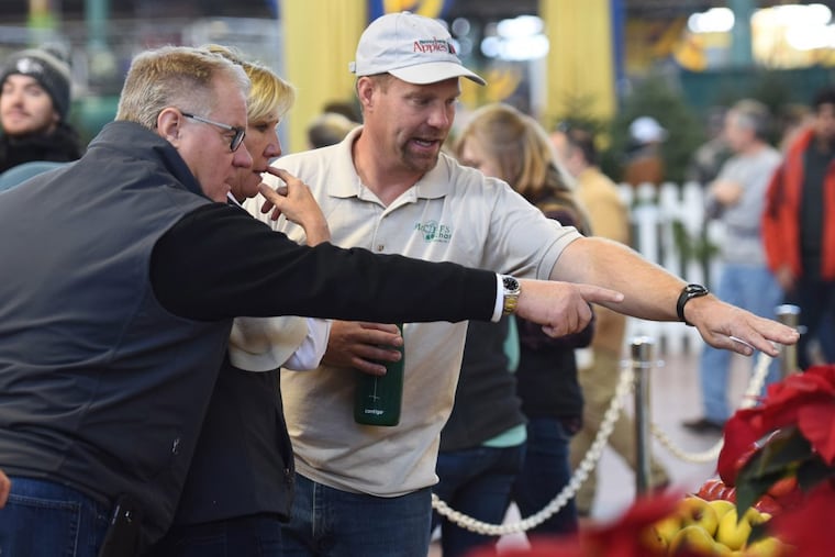 State Sen. Scott Wagner, R-York, left, along with his wife, Tracy, center, and apple orchard owner Corey McCleaf, right, inspect apples on display at the Pennsylvania Farm show on Sunday, Jan. 7, 2018 in Harrisburg, Pa.