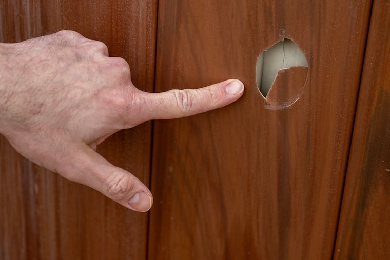 Guy Holzman points to a hole in his fence at Cherry Hill home Monday Mar. 17, 2025. He says it was made by one of the many foul balls from the baseball field at Cherry Hill High School East that land in his yard and is threatening legal action against the school.