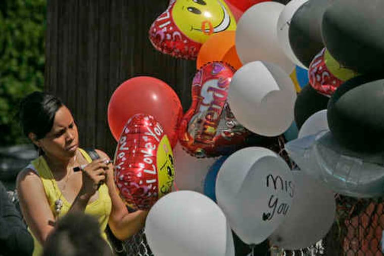 At a memorial for Rasheem Butcher, Gia Grier signs a balloon she put at the site where the 13-year-old died. The SUV he was driving flipped Wednesday night during a police chase.