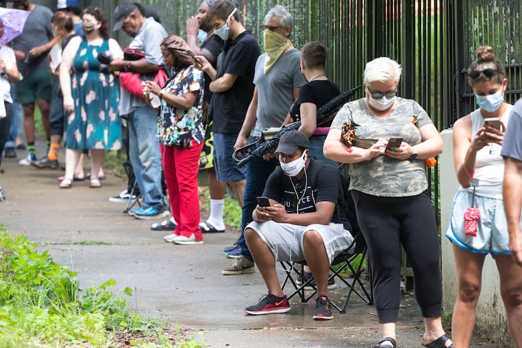 Steven Posey checks his phone as he waits in line to vote at Central Park in Atlanta. Voters reported wait times of three hours.