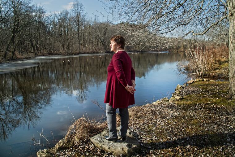 Alice Johnston looks at Kirkwood Lake behind her home's backyard in Voorhees. The man-made lake is dying of eutrophication and sedimentation, but dredging may not be possible until upstream work on a massive Superfund site in Gibbsboro is completed.
