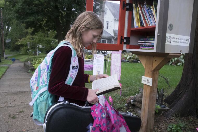 10-year-old Genevieve Chermside stops on her way from school and picks out a book from the little library at Margit Novack's home in Ardmore.