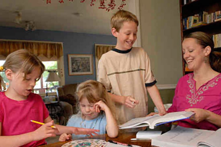 Gena Conley works with Jessa, 7, Ellie, 4, and Gabe, 11 , in their dining room. She loves the autonomy and family time that homeschooling allows. (April Saul / Staff)