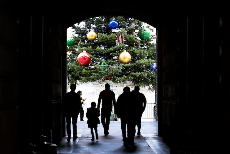 Pedestrians walked through a doorway at City Hall while approaching a 55-foot-tall Christmas tree.