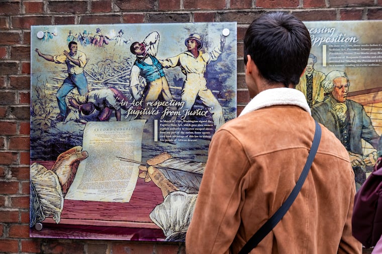 A visitor reads a sign describing the Fugitive Slave Act of 1793 at the President’s House at Independence National Historic Park on Sept. 16. The painting is among the exhibits at the park flagged under President Donald Trump's order.