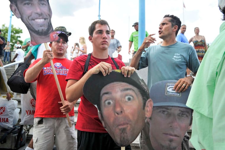TOM GRALISH / STAFF PHOTOGRAPHER IT'S A CASE of bass hysteria along the Delaware River yesterday as a crowd (above) - including Nicholas Orsino (left), his cousin Zach Orsino (center) and Zach's father, Frank (right) - show that they've fallen hook, line and sinker for, and are waiting to get an autograph from, master fisherman Michael Iaconelli. (That's Iaconelli's face the trio are displaying.) And that's Philly-born South Jerseyan Iaconelli (left) displaying one of his catches at the Great Plaza on Penn's Landing after winning the Bassmaster Elite Series Professional Tournament, which drew about 100 of the world's best anglers to our local waters over the weekend.