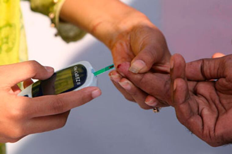 A volunteer uses glucometer to test the blood sugar level of a man at a free diabetes check-up camp to mark World Diabetes Day. (AP Photo/Pavel Rahman)